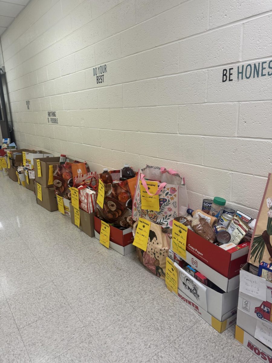 Bags of food donations lined up in the halls of the time out room prepared to be given to each family. Each bag is stamped with a paper containing the number of which family it will be given to and, most times, it also contains a kind message for the holiday season. (Amelia Kasten)