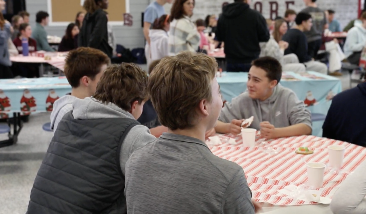 Students gather together around tables to play games. 
